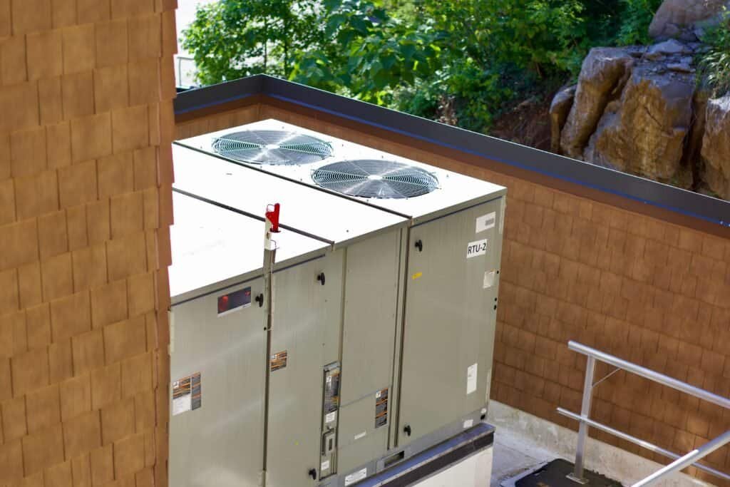 HVAC air conditioning unit on rooftop with trees in background.